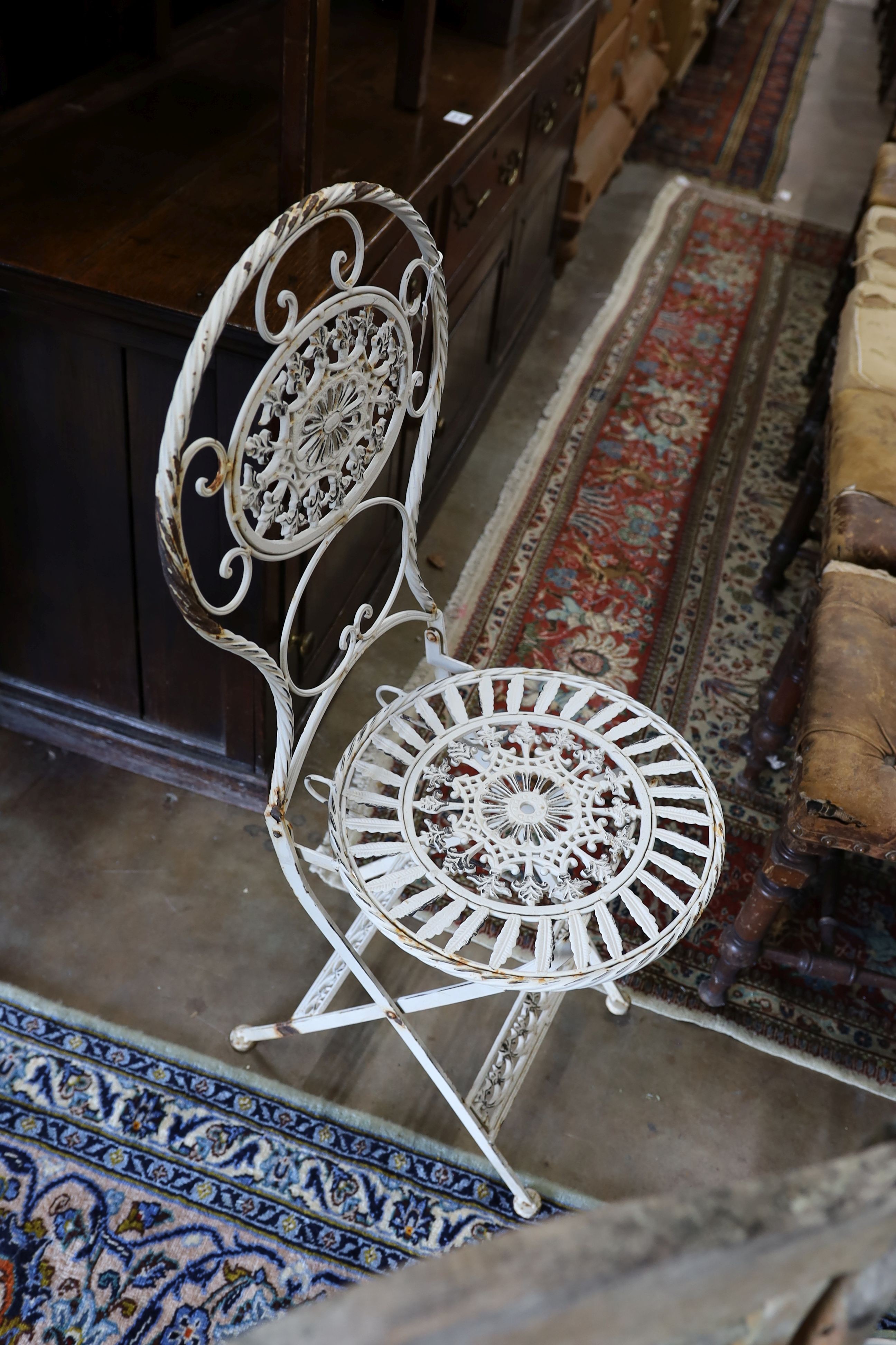 A wrought iron circular garden table, diameter 65cm, height 74cm and four folding chairs